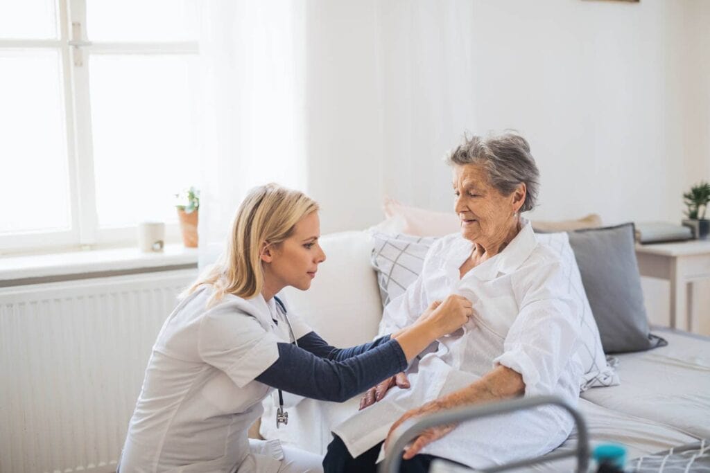 Grundpflege zu Hause: Pflegekraft von Kardia unterstützt eine Seniorin beim Ankleiden
