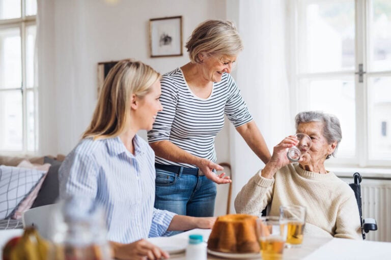 Pflegekraft von Kardia im Austausch mit Seniorin und Angehöriger beim gemeinsamen Kaffeetrinken zu Hause
