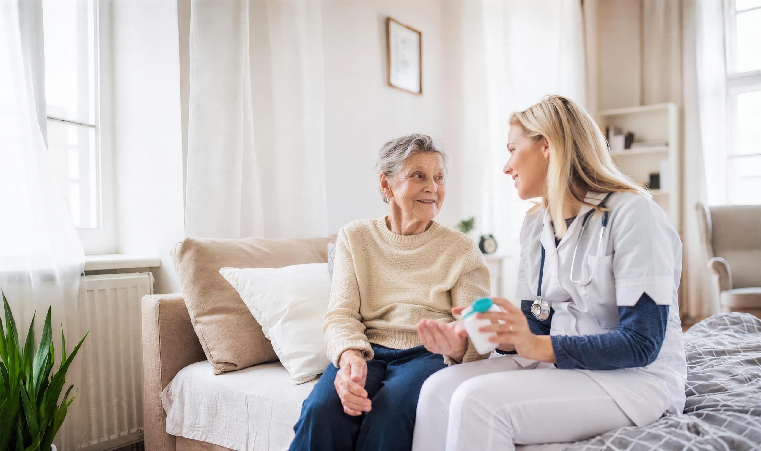Ambulante Pflege zu Hause: Pflegekraft von Kardia bespricht mit einer lächelnden Seniorin die Medikamenteneinnahme